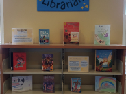 Children's book display with books, artwork, and a poster
