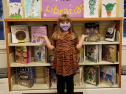 Little girl proudly standing in front of a full book display