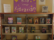 A children's book display with middle grade books, a couple of posters, and some artwork
