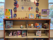 Books, art, and decorations displayed on library bookshelves.