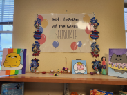 A closeup of art and decorations displayed on library bookshelves.