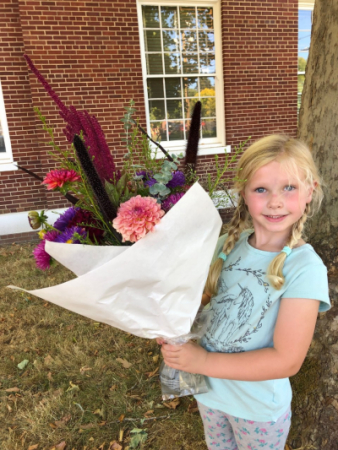 A little girl holding a big bouquet of flowers.