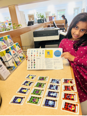 Girl standing next to a counter with Reading Dragon cards laid out.