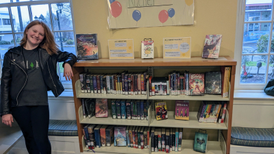 Young woman standing next to bookshelves