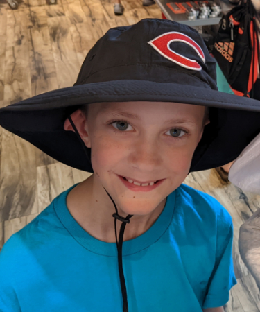 Picture of boy wearing a blue shirt and a Camas hat.