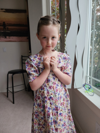 Finley standing next to a window in a flower dress